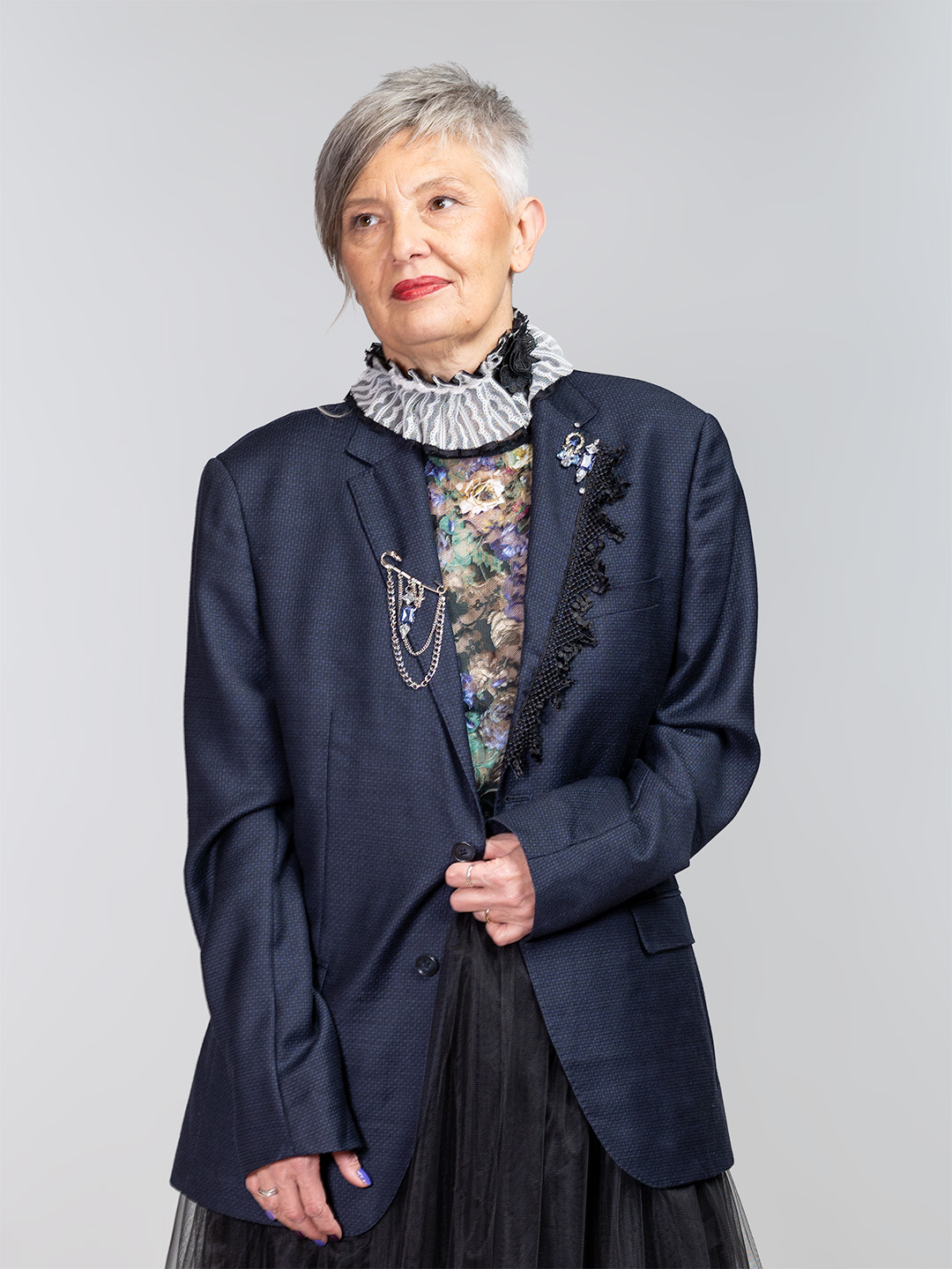 Tamnoplavi upcycled sako ukrašen crnom čipkom i srebrnim broševima s lancima, u kombinaciji s raskošnom crnom suknjom od tila.