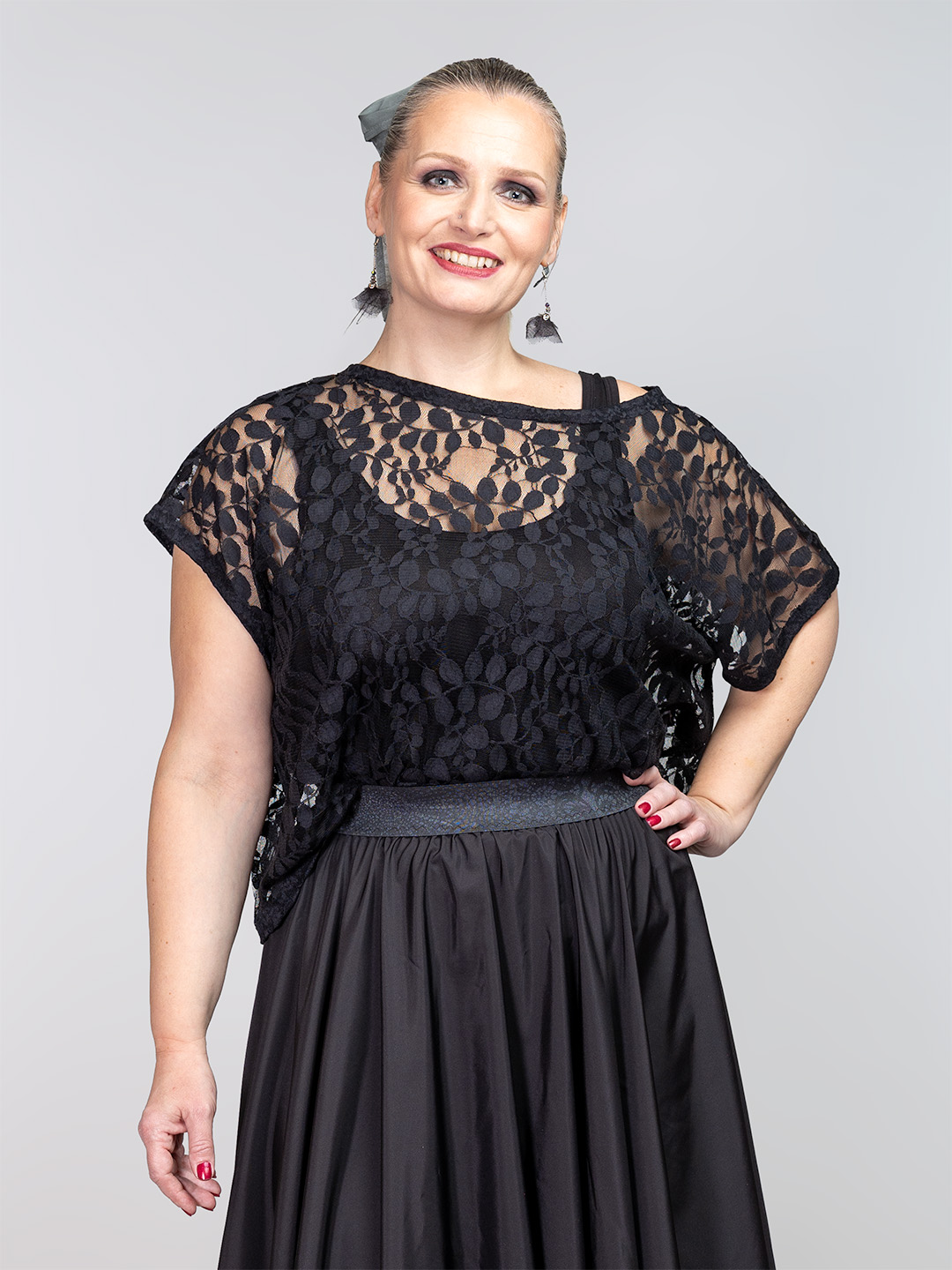 Proziran crni čipkasti top s uzorkom lišća preko crne majice, u kombinaciji s dugom crnom suknjom.