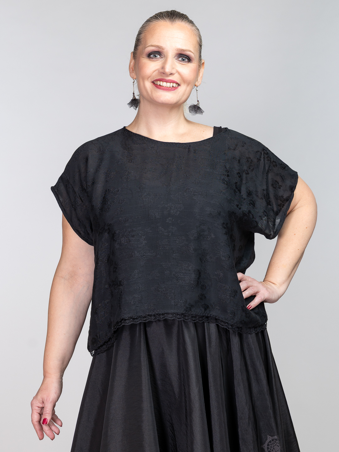 Crni top od viskoze s reljefnim cvjetnim uzorkom i čipkastim rubom u kombinaciji s dugom crnom suknjom.