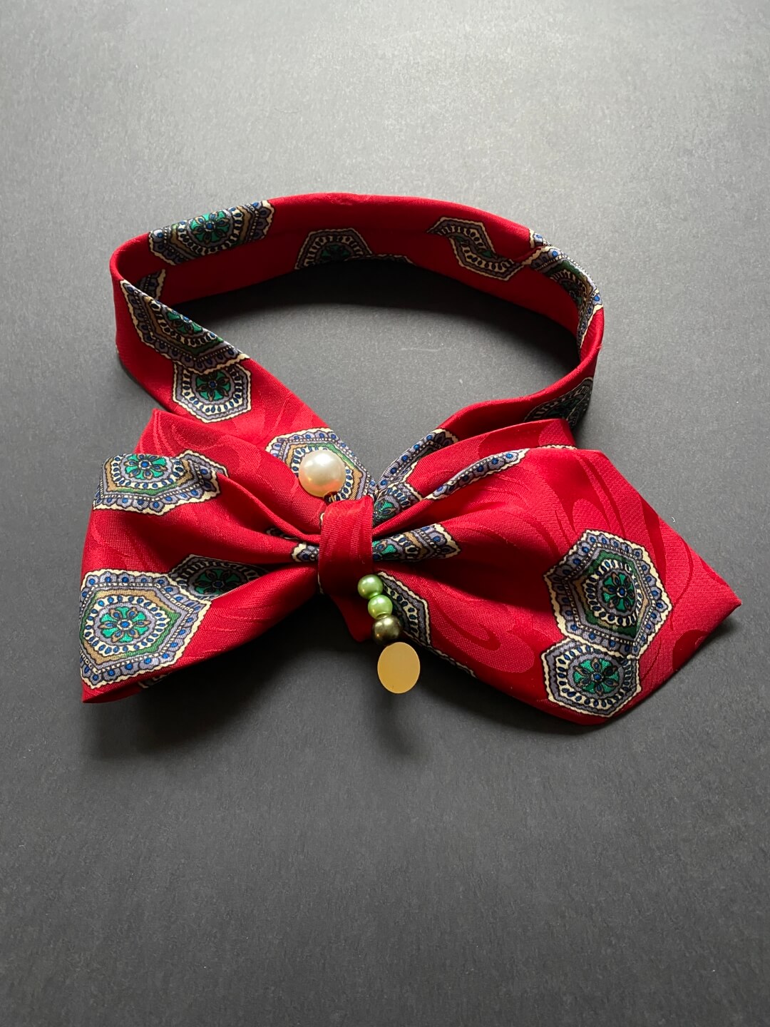 Crvena unikatna mašna-kravata ukrašena ukrasnom iglom s biserima