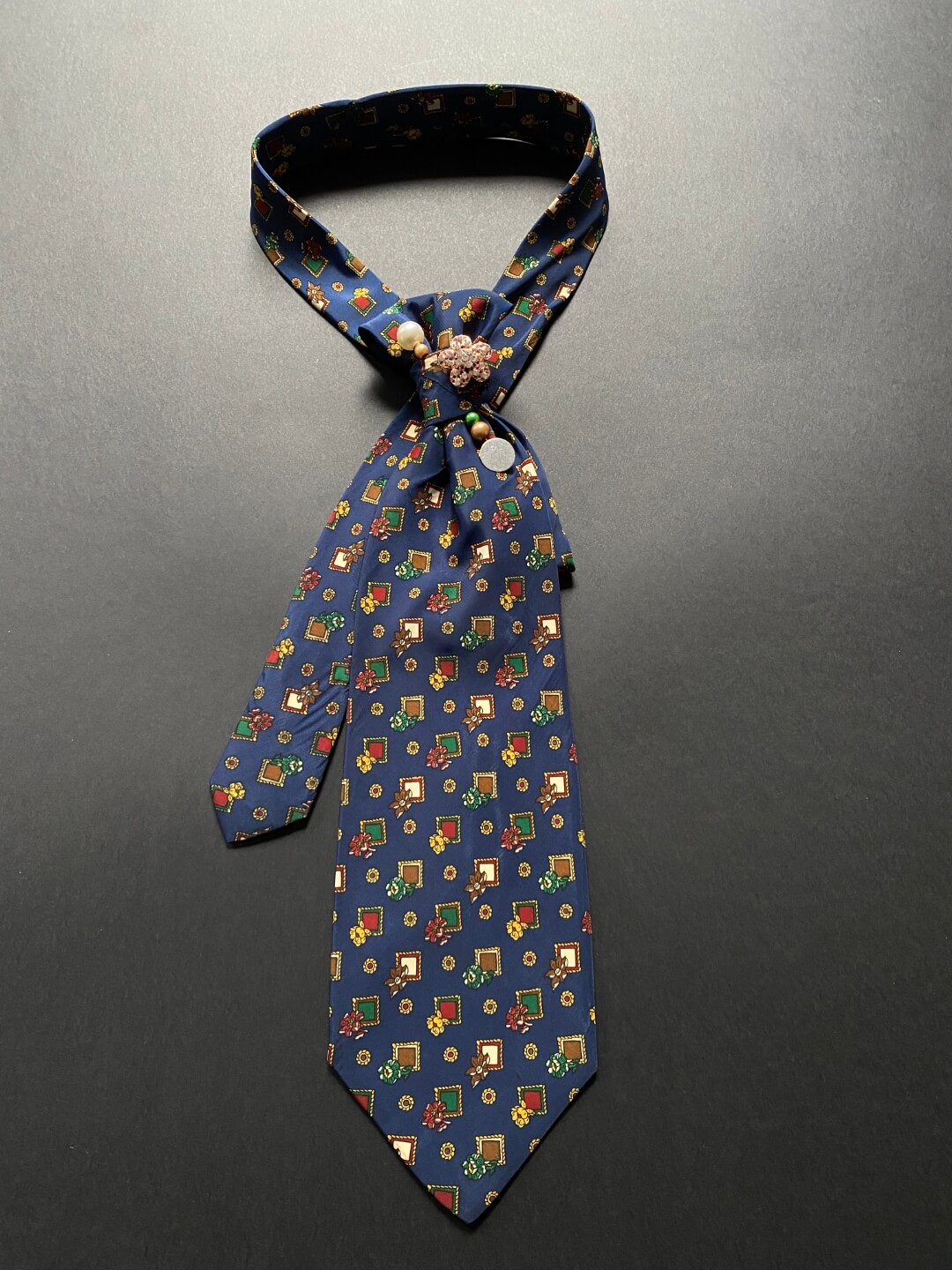 Tamno plava ženska unikatna kravata s uzorkom cvjetića ukrašena brošem i ukrasnom iglom