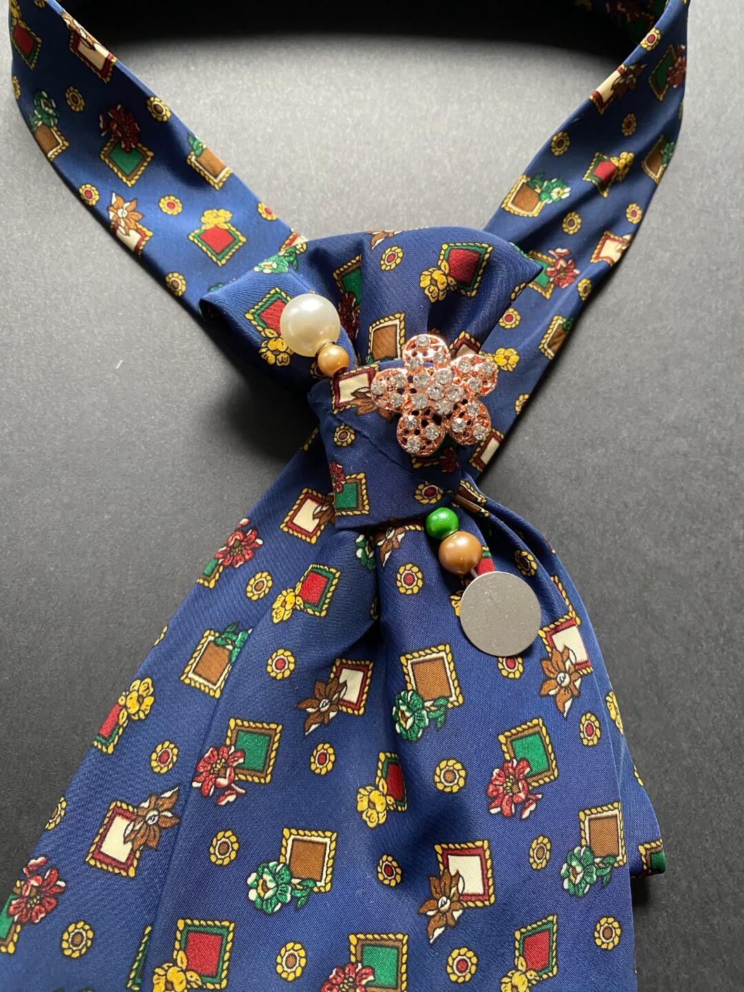 Tamno plava ženska unikatna kravata s uzorkom cvjetića ukrašena brošem i ukrasnom iglom