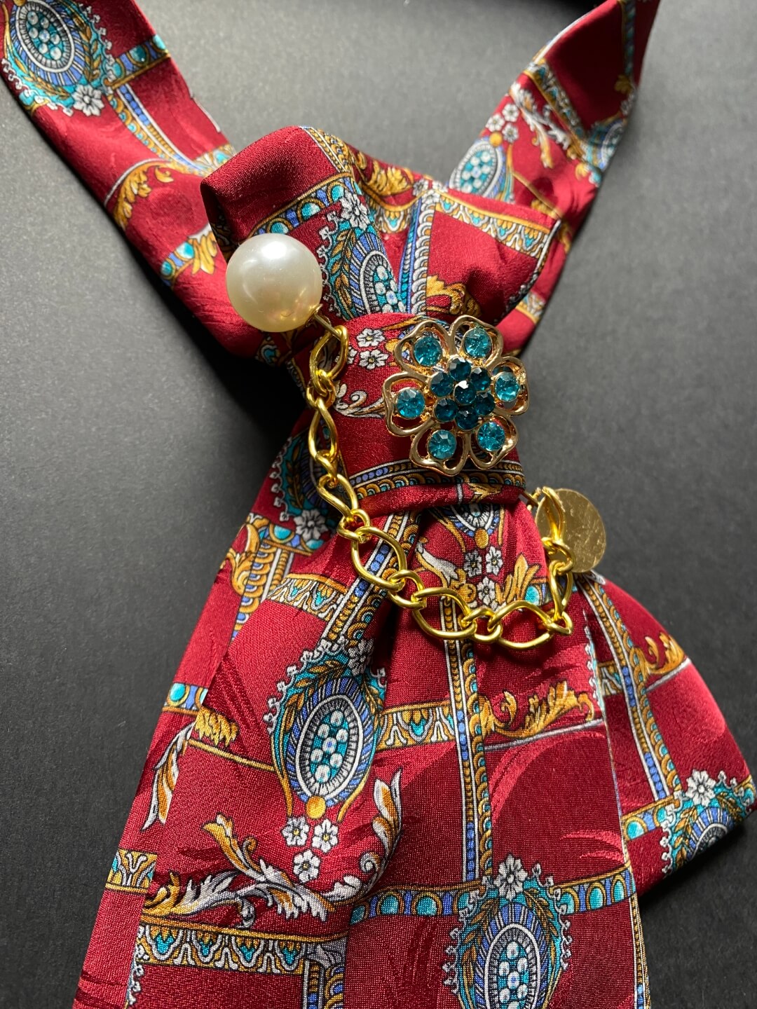 Unikatna crvena ženska kravata s baroknim uzorkom plave i zlatne boje ukrašena brošem i iglom