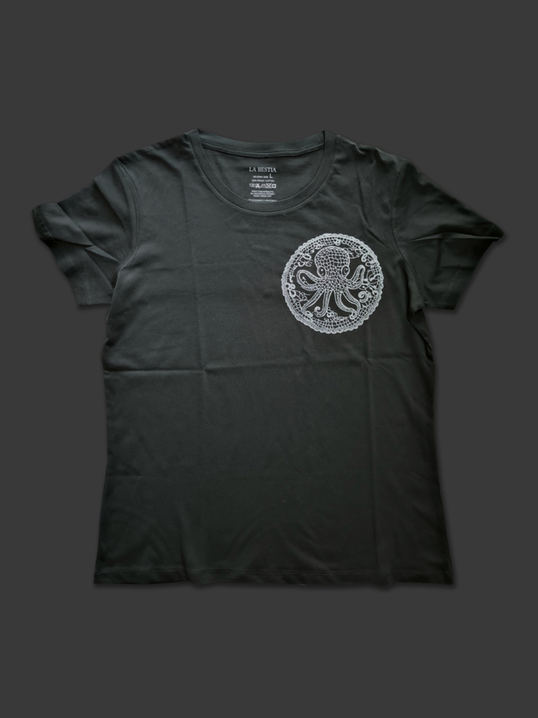 Crna ženska pamučna majica sa srebrnim printom hobotnice u krugu od čipke na lijevoj strani prsa, asimetričan dizajn.