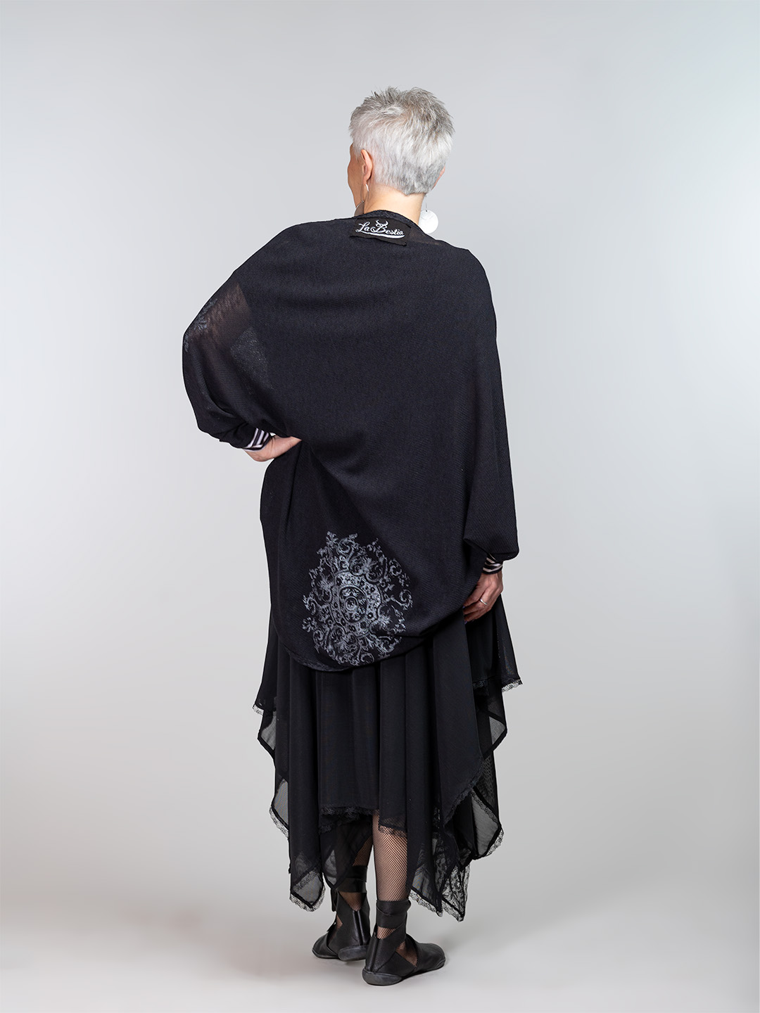 Crna ženska vesta izrađena od laganog pletiva s tiskom srebrne čipke i crna asimetrična suknja