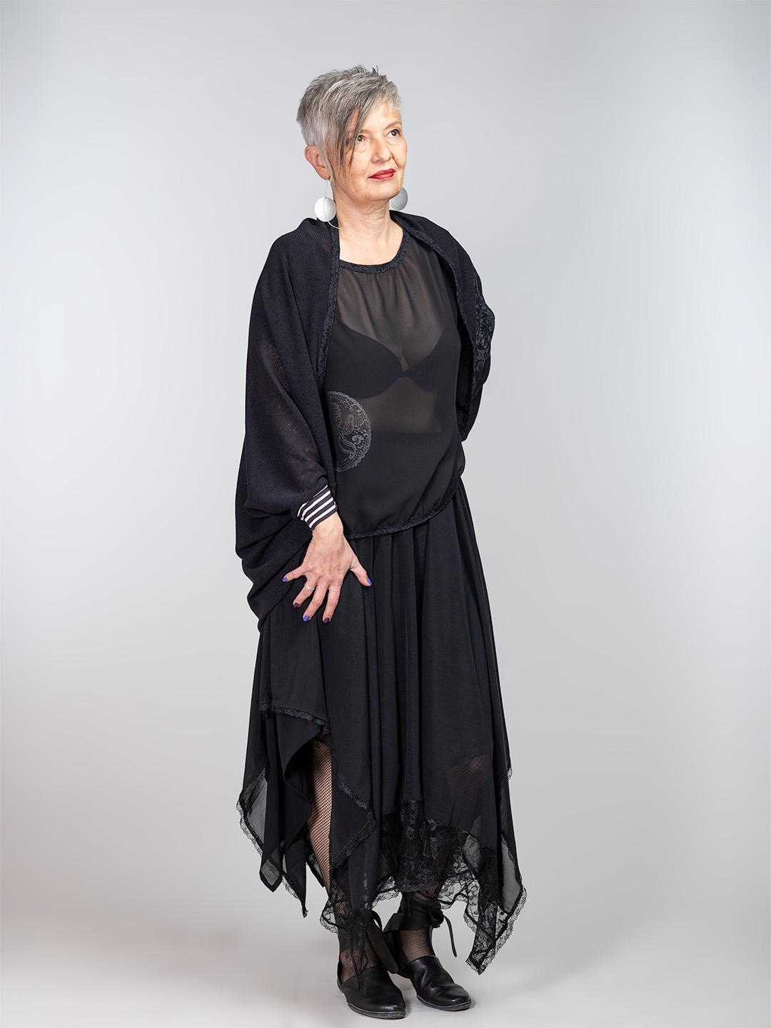 Crna ženska vesta izrađena od laganog pletiva s tiskom srebrne čipke i crna asimetrična suknja